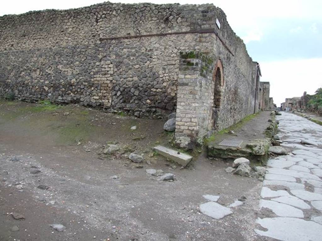 Pompeii II.4.7a. December 2005. Street shrine on north-east corner of II.4.  Looking west along Via dell’Abbondanza from Vicolo dell’ Anfiteatro. 
According to Garcia y Garcia, the same two bombs that fell on 19th September 1943, also destroyed the remains of a roofed portal that could close Vicolo dell’ Anfiteatro at its north end. This gateway would have closed the vicolo, which provided the only access by carts, wagons and chariots to the amphitheatre or Palaestra, as a form of traffic-control. Only the pilaster, on the north-east side, which supported this street portal has been restored. See Garcia y Garcia, L., 2006. Danni di guerra a Pompei. Rome: L’Erma di Bretschneider. (p.46)

