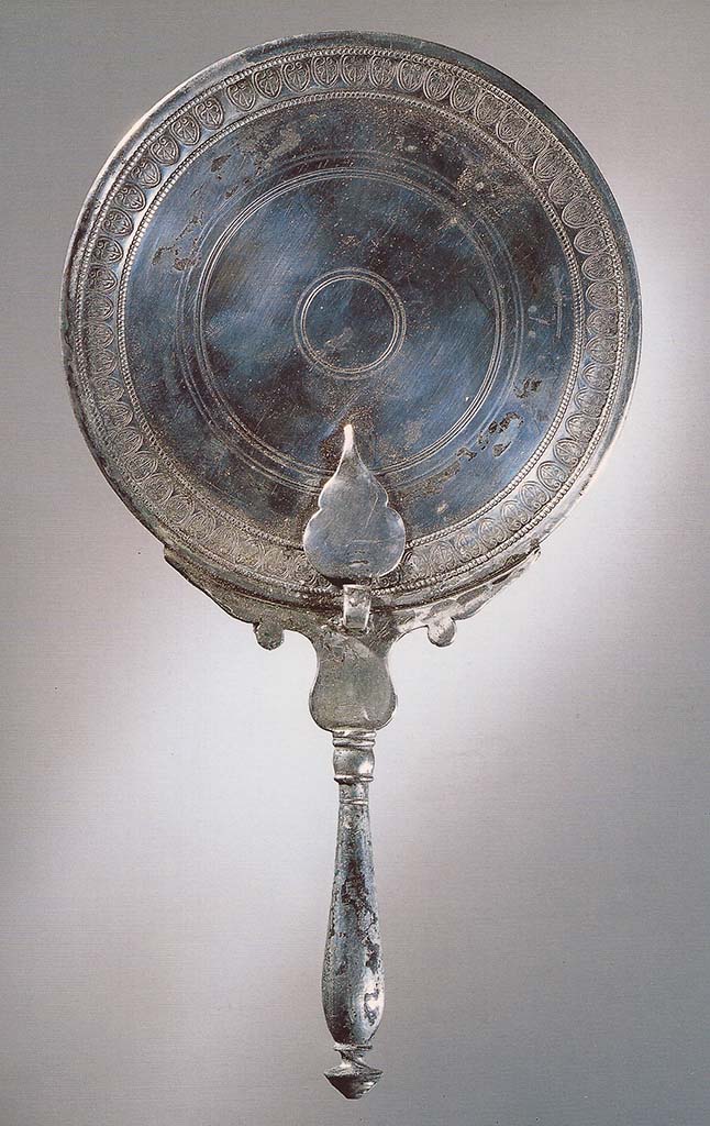 Victim numbered 4. Silver mirror with a border decorated with a series of incised palmettes.
Now in Naples Archaeological Museum. Inventory number 25716.
