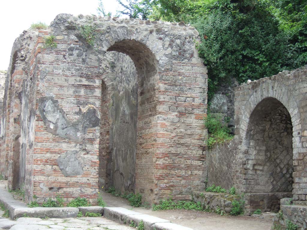 Pompeii Porta Ercolano or Herculaneum Gate. May 2006. 
Looking south towards west side from Via dei Sepolcri with Tomb of M. Cerrinius Restitutus, on right. 
According to Van der Graaff –
“At the Porta Ercolano, during the excavations next to the Tomb of M. Cerrinius Restitutus, Maiuri recovered a stratum filled with votive offerings including small terracotta vases as well as fragments of figurines…………………. 
Maiuri ascribed the deposit to a vanished religious sacellum dedicated to Venus or Minerva that was associated with the Samnite gate. 
It would have served the gate throughout its history right up to its reconstruction after the earthquake.”
See Van der Graaff, I. (2018). The Fortifications of Pompeii and Ancient Italy. Routledge, (p.211).
