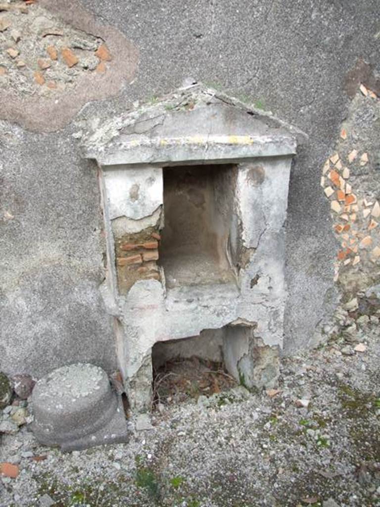 IX.3.15 Pompeii. March 2009. Room 12, aedicula lararium.
According to Boyce, the base (h.0.85 by 0.30, h.0.70) contained a large rectangular recess (h.0.50, w.0.56, d.0.53) coated with white stucco.
Above it the two thick (0.25) side walls support a pediment  and with the east wall  of the room form a rectangular niche (h.0.65, w.0.35, d.0.60).
In the back wall of the rectangular niche was a semi-circular recess.
The interior was decorated with red spots on a white background.
The tympanum was blue. There were red stripes dividing the exterior of the structure into sections.
This shrine is nowhere mentioned in the excavation reports.
See Boyce G. K., 1937. Corpus of the Lararia of Pompeii. Rome: MAAR 14. (p. 84, no. 414, Pl. 34, 1) 


