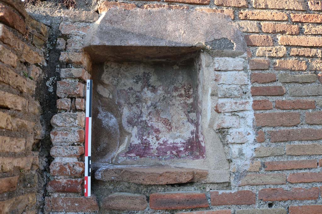 V.1.30 Pompeii. December 2018. Detail of niche from west end of north wall. Photo courtesy of Aude Durand.
According to Boyce, the small rectangular niche (h.0.33, w.0.30, d.0.12, h. above floor 2.10), was high up on north wall.
The rear wall of the niche was last painted red with a blue border.
Underneath this last coat of plaster, several earlier ones could be distinguished. 
See Boyce G. K., 1937. Corpus of the Lararia of Pompeii. Rome: MAAR 14. (p .33, no.82) 
