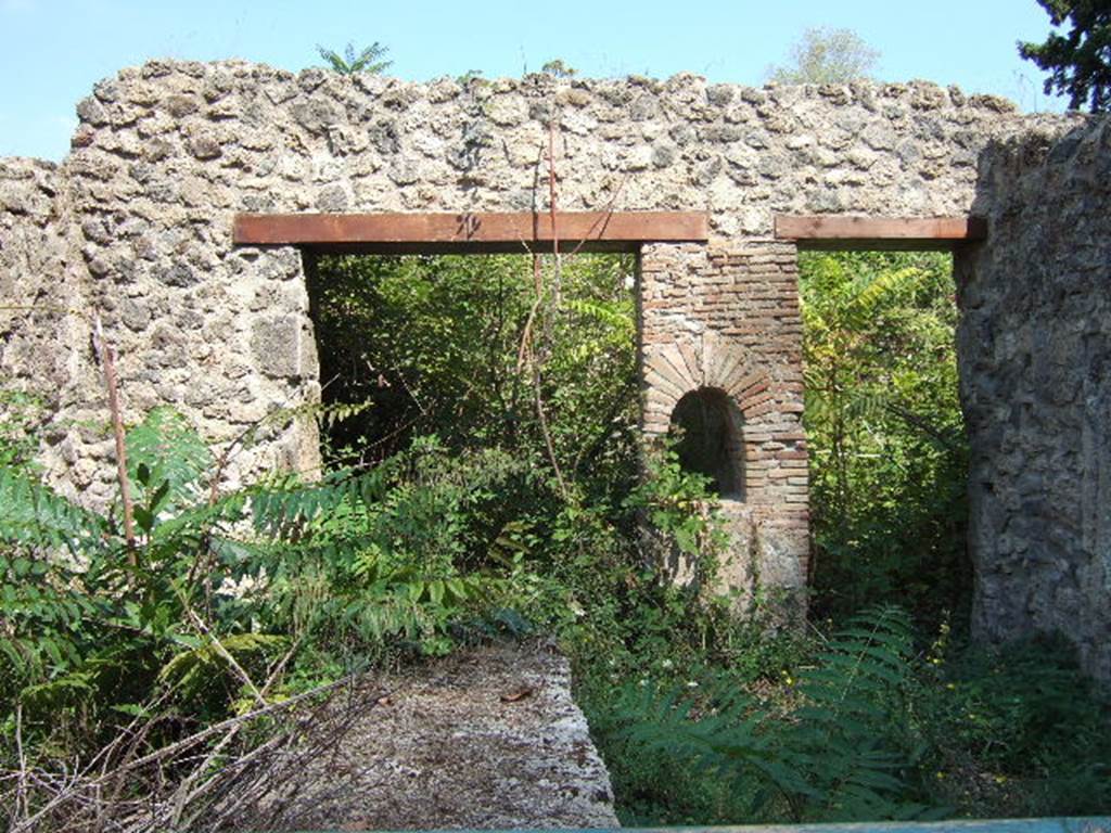 I.1.2 Pompeii. September 2005. In front, remains of podium in selling room. 
At the rear are entrances to two rear rooms. The one on the left (north side) was the dining room for the customers and had painted walls, where one could have a glimpse of Phryxus sitting on a ram, extending his hand to Helle to pull her from the waves. 
The other larger rustic room, on the south,  contained the kitchen with hearth, the latrine and steps to the upper floor dwelling.
See Pappalardo, U., 2001. La Descrizione di Pompei per Giuseppe Fiorelli (1875). Napoli: Massa Editore. (p.33)
