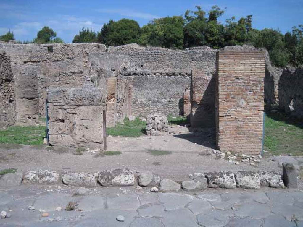 I.1.4 Pompeii. September 2010. Entrance, looking east east from Via Stabiana.Photo courtesy of Drew Baker.
According to Warscher, quoting Mau in Bull. Inst. 1875, p.29, 
I.1.4/5 - Mentre le localit servivano per i carri e per il bestiame da tiro e come camere da letto, lungo la strada, a sinistra dello ingresso, stanno altre localit (nos.4 and 5) che evidentemente servivano da caupona per i carrettieri e per altri avventori.  Vi sono due locali con larga apertura sulla strada, a guisa di botteghe, congiunte mediante una porta, e in ciascuno di cui d unaltra stanza con apertura larga anchessa, queste ultime non congiunte fra di loro, mentre quella meridionale ha una porta su quel locale per cui si passa nel cortile. In mezzo al locale anteriore no.4 si trova una tavola di materiale piuttosto piccola, sulla quale si metteva senza dubbio una tavola pi grande di legno per mangiare.  Avanti alla porta del locale no.5 e lungo il muro laterale della casa adiacente, che sporge un poco nella strada, vi  una panca di materiale, quale trovammo avanti alla caupona (also see I.1.6/9)
See Warscher T., 1936. Codex Topographicus Pompeianus: Regio I.1, I.5. (no.13), Rome: DAIR, whose copyright it remains.
(translation: While the locality served for wagons and animals and as sleeping accommodation, along the road, to the left of the entrance, were other places (nos. 4 and 5) that evidently served as caupona for the carters and other patrons.  There were two rooms with a wide opening onto the road in the guise of shops, joined through a door, and in each of which had another different room also with a wide opening, these last did not join each other, while the southern one had a door which passed into the courtyard.  In the middle of the front room of no. 4 was a table of material, rather small, on which one would undoubtedly have placed a larger wooden table for eating. Before the door of the premises no. 5 and along the side wall of the adjacent house, which protruded a little into the street, there was a bench of material, which was found before the caupona.)