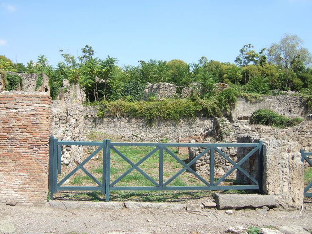 I.1.8 Pompeii, on left, and I.1.7 Pompeii, stairs to upper floor, on right. September 2005.
According to Warscher, quoting Mau in Bull.Inst 1875, p.30, I.1.6-9: Segue un altro albergo, molto simile a questo descritto.  Qui pure  interrotto il marciapiede per lasciar entrare i legni. Lentrata era chiuse mediante una porta a quattro partiti, congiunti a due adue, come si conosce dai quattro buchi per i chiavistelli.  Qui pure si entra prima in un compreso che ha le dimensioni duna bottega grande con una dietrobottega e posteriormente si apre sopra una grande corte, lungo il cui muro di fondo qui pure si stende la stalla, larga 13,30, profonda 2,47 con una finestra sul vico settentrionale e due porte, una allestremit meridionale, laltra poco distante da quella settentrionale. 
Presso a questultima una parte della corte  selciata.  Lungo il muro N vi sono due camere con finestre sul medesimo vico, e prossimo alla stalla il cesso.  Si vede anche il cesso del piano superiore e i tubi di mattone dun terzo, che stava ancora pi in alto.  
Nellangolo NO vi sono I primi gradini duna scala, la cui parte superiore sar stata di legno, in quello SO lapertura della cisterna, e accanto nella stessa massa di materiale una vasca lunga stretta e bassa, come quella sudescritta nella casa adiacente. Qui la vediamo frapposto fra la cisterna ed il muro di O, il che esclude categoricamente laver essa servito dabbeveratoio. Dalla parte pi bassa di essa, aperta come nella casa sudescritta, lacqua colava in unaltra vasca larga 1,02 x 1,54, di cui un lato viene formato dalla suddetta massa di fabbrica, uno dal muro occidentale, i due rimanenti da appositi muricciuoli.  Essa ha al fondo uno scolo verso N, che d in un vaso ossia tubo di mattone, incastrato nel suolo. Nella parete vi era la pittura dei Lari, di cui sono rimasti soltanto i serpi. A destra dellingresso per i legni sta un locale come una bottega. 
Lessere esso congiunto mediante una porta con quel primo compreso, ove entravano i legni, ci lascia supporre, aver esso servito di caupona per i vetturini.
See Warscher T., 1935. Codex Topographicus Pompeianus: Regio I.1/I.5. Rome: DAIR. (no.14)
(for a translation see, I.1.6).

