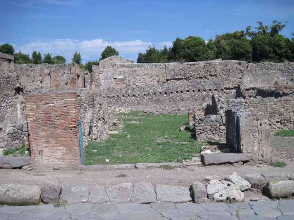 I.1.8 Pompeii. September 2010. Entrance doorway, looking east from Via Stabiana.
The entrance for I.1.7 is on the right side of the entrance). Photo courtesy of Drew Baker.

According to Warscher, quoting Mau in Bull.Inst 1875, p.30, I.1.6-9: “Segue un altro albergo, molto simile a questo descritto.  Qui pure è interrotto il marciapiede per lasciar entrare i legni. L’entrata era chiuse mediante una porta a quattro partiti, congiunti a due adue, come si conosce dai quattro buchi per i chiavistelli.  Qui pure si entra prima in un compreso che ha le dimensioni d’una bottega grande con una dietrobottega e posteriormente si apre sopra una grande corte, lungo il cui muro di fondo qui pure si stende la stalla, larga 13,30, profonda 2,47 con una finestra sul vico settentrionale e due porte, una all’estremità meridionale, l’altra poco distante da quella settentrionale. 
Presso a quest’ultima una parte della corte è selciata.  Lungo il muro N vi sono due camere con finestre sul medesimo vico, e prossimo alla stalla il cesso. Si vede anche il cesso del piano superiore e i tubi di mattone d’un terzo, che stava ancora più in alto.  
Nell’angolo NO vi sono I primi gradini d’una scala, la cui parte superiore sarà stata di legno, in quello SO l’apertura della cisterna, e accanto nella stessa massa di materiale una vasca lunga stretta e bassa, come quella sudescritta nella casa adiacente. Qui la vediamo frapposto fra la cisterna ed il muro di O, il che esclude categoricamente l’aver essa servito d’abbeveratoio. Dalla parte più bassa di essa, aperta come nella casa sudescritta, l’acqua colava in un’altra vasca larga 1,02 x 1,54, di cui un lato viene formato dalla suddetta massa di fabbrica, uno dal muro occidentale, i due rimanenti da appositi muricciuoli.  Essa ha al fondo uno scolo verso N, che dà in un vaso ossia tubo di mattone, incastrato nel suolo. Nella parete vi era la pittura dei Lari, di cui sono rimasti soltanto i serpi. A destra dell’ingresso per i legni sta un locale come una bottega. 
L’essere esso congiunto mediante una porta con quel primo compreso, ove entravano i legni, ci lascia supporre, aver esso servito di caupona per i vetturini”.
See Warscher T., 1935. Codex Topographicus Pompeianus: Regio I.1/I.5. Rome: DAIR. (no.14)
(for a translation see, I.1.6).