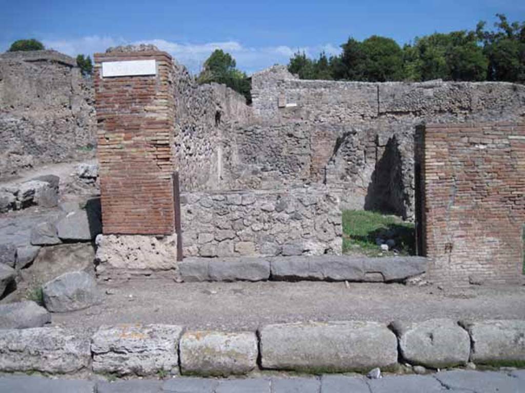 I.1.9 Pompeii. September 2010. Entrance doorway, looking east from Via Stabiana.
Photo courtesy of Drew Baker.

According to Warscher, quoting Mau in Bull.Inst 1875, p.30, I.1.6-9: Segue un altro albergo, molto simile a questo descritto.  Qui pure  interrotto il marciapiede per lasciar entrare i legni. Lentrata era chiuse mediante una porta a quattro partiti, congiunti a due adue, come si conosce dai quattro buchi per i chiavistelli. Qui pure si entra prima in un compreso che ha le dimensioni duna bottega grande con una dietrobottega e posteriormente si apre sopra una grande corte, lungo il cui muro di fondo qui pure si stende la stalla, larga 13,30, profonda 2,47 con una finestra sul vico settentrionale e due porte, una allestremit meridionale, laltra poco distante da quella settentrionale. 
Presso a questultima una parte della corte  selciata.  Lungo il muro N vi sono due camere con finestre sul medesimo vico, e prossimo alla stalla il cesso. Si vede anche il cesso del piano superiore e i tubi di mattone dun terzo, che stava ancora pi in alto.  
Nellangolo NO vi sono I primi gradini duna scala, la cui parte superiore sar stata di legno, in quello SO lapertura della cisterna, e accanto nella stessa massa di materiale una vasca lunga stretta e bassa, come quella sudescritta nella casa adiacente. Qui la vediamo frapposto fra la cisterna ed il muro di O, il che esclude categoricamente laver essa servito dabbeveratoio. Dalla parte pi bassa di essa, aperta come nella casa sudescritta, lacqua colava in unaltra vasca larga 1,02 x 1,54, di cui un lato viene formato dalla suddetta massa di fabbrica, uno dal muro occidentale, i due rimanenti da appositi muricciuoli.  Essa ha al fondo uno scolo verso N, che d in un vaso ossia tubo di mattone, incastrato nel suolo.Nella parete vi era la pittura dei Lari, di cui sono rimasti soltanto i serpi.A destra dellingresso per i legni sta un locale come una bottega. 
Lessere esso congiunto mediante una porta con quel primo compreso, ove entravano i legni, ci lascia supporre, aver esso servito di caupona per i vetturini.
See Warscher T., 1935. Codex Topographicus Pompeianus: Regio I.1/I.5. Rome: DAIR. (no.14)
(for a translation see, I.1.6).
