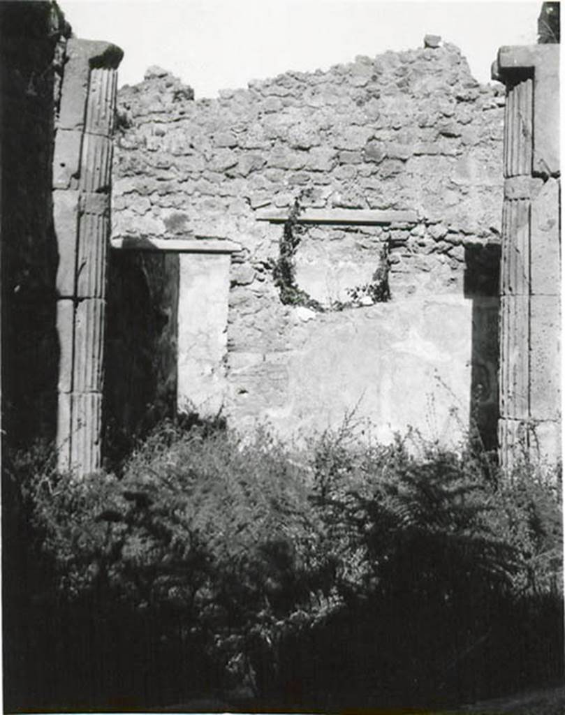 I.2.3 Pompeii. 1935 photo taken by Tatiana Warscher. Looking north.
Warscher described this photo as – I.2.3 “Il triclinio (h): una specie di piccolo vestibulo a sinistra (nord) è ornato con due mezzocolonne di tufo scannelate.  Non è rimasto niente nè della pittura del Genio familiare che libava, nè del dipinto del gallo sull’ara. In connessione con la colonna intercalata nel muro nord della prima camera a sinistra dell’atrio (photo no.8) facciamo attenzione che nel muro occidentale del triclinio sono intercalati due tamburi d’una colonna.  Forse il proprietario ricostruendo la casa dopo il terremoto dell’anno 63 ha acquistato una colonna, due tamburi e anche due mezzocolonne scannellate. 
Quoting Sogliano, no.58 on page 18, she described: Cella penaria: “Serpente che si accosta all’ara imbandita di offerte; al di sotto piante palustri e al di sopra tre piccoli festoni di foglie, sormontati ciascuno da un uccelletto”.
See Sogliano, A., 1879. Le pitture murali campane scoverte negli anni 1867-79. Napoli: Giannini. (p.18, no.58)
See Warscher T., 1935. Codex Topographicus Pompeianus: Regio I.2. (no.11), Rome: DAIR, whose copyright it remains.   
(translation: I. 2.3 "triclinium (h): a small vestibule on the left (north side) was adorned with two fluted tufa half-columns.  There remained nothing of the painting of the family Genius making the offering, nor of the painting of the cock painted on the altar.  In connection with the column inserted in the northern wall of the room to the left of the entrance hall (photo no. 8) we draw attention that in the west wall of the triclinium were interspersed two column drums.  Maybe the owner by rebuilding the house after the earthquake of the year 63 had bought a column, two drums and also two fluted half-columns”. 
Quoting Sogliano, no. 58 on page 18, she described: 
Storeroom : "Serpent approaching the altar table laid with offerings; marsh plants below and three small garlands festoons of foliage above, each surmounted by a bird”.)
