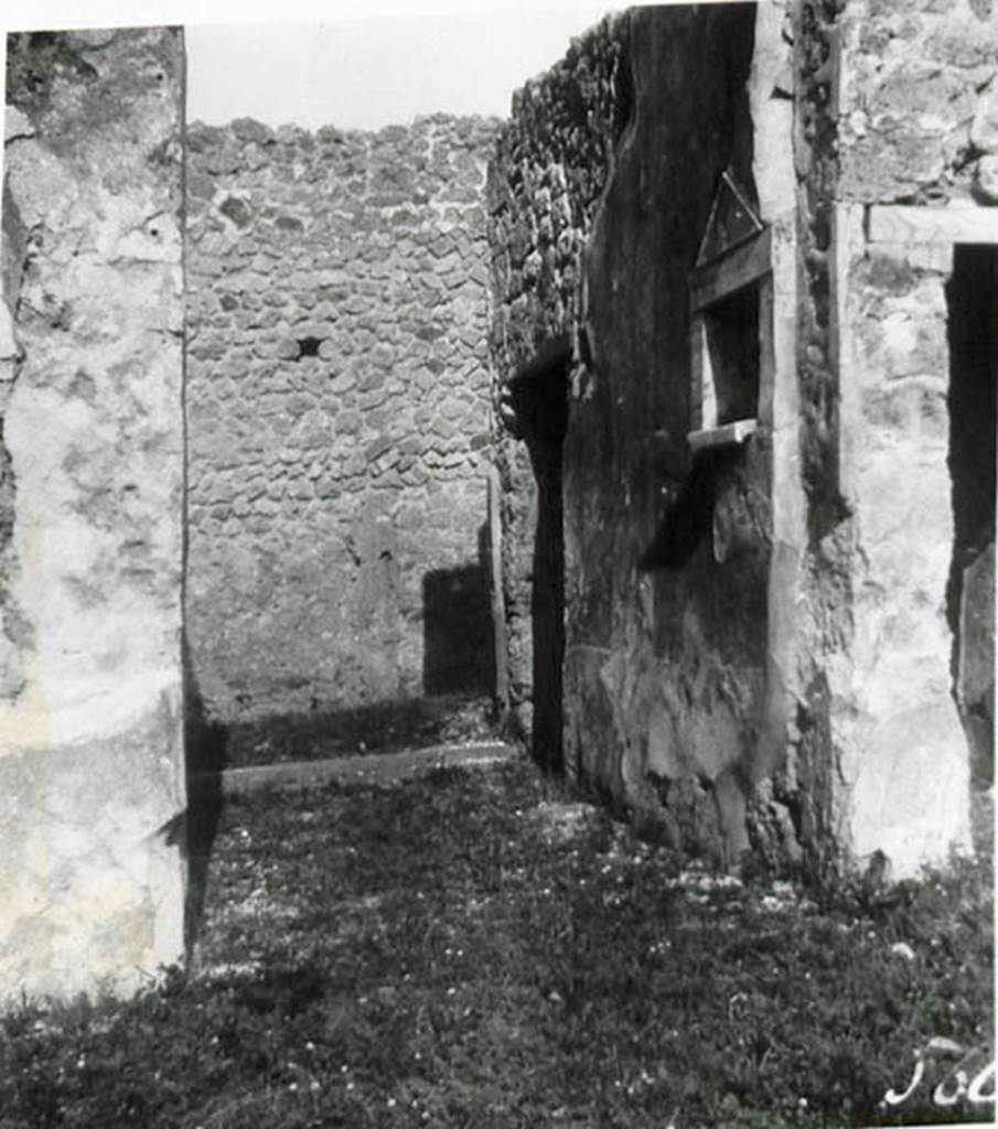 1.2.17 Pompeii. 1935 photo taken by Tatiana Warscher. Looking north along entrance corridor towards doorway.
See Warscher T., 1935. Codex Topographicus Pompeianus: Regio I.2. (no.28), Rome: DAIR, whose copyright it remains.
According to Warscher, quoting Bull. Inst, 1874, p.264  I.2.17 La fauces che hanno la soglia di lava, sabbassano un poco verso linterno.  Nel muro sinistra vi  una piccola nicchia con suole e cornice di marmo a guisa dun tempietto. Nel suole di essa sono tre buchi, uno pi profondo degli altri destinati probabilmente per mettervi piccoli idoli, come la lastra sporgente del suolo serviva per oblazioni. Presso gli angoli che formano le fauces collatrio manca lo stucco del muro, e nel suolo su ciascun lato si vede una pietra di lava: evidentemente vi stavano li postes di legno.
(translation: I.2.17 The fauces that had a threshold of lava, led slightly downwards towards the atrium. In the left wall there was a small niche with floor and cornice of marble, in the guise of a shrine. In the floor were three holes, one deeper than the others, which was used probably for a small idol, and the protruding slab of the floor was used for donations. Near the corner that joined the fauces with the atrium, the wall stucco was missing and in the floor on that side one could see a slab of lava: evidently there were wooden posts.) 
