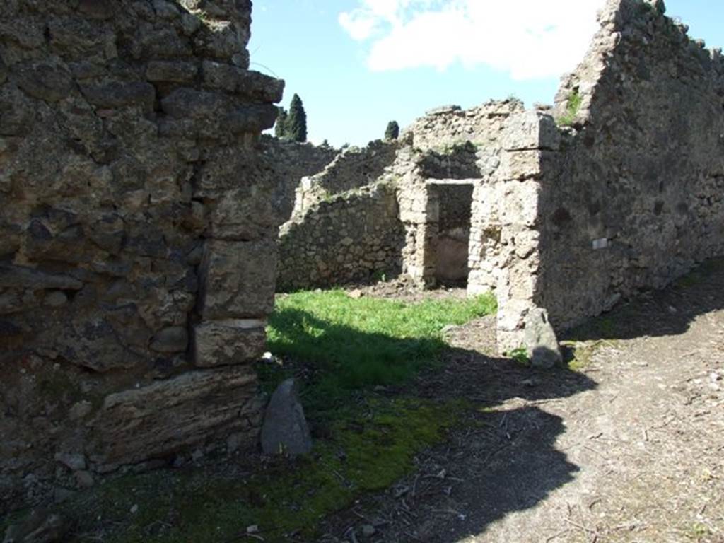 I.2.22 Pompeii. March 2009. Entrance, looking north-west. According to Warscher, quoting Mau in Bull. Inst. 1874, p.263, she described  I.2.22 Le case che verso E danno sul vico di Tesmo, non meritano una descrizione dettagliata. Rilevo soltanto che nella prima casa verso S a destra duno stretto corridoio si trova prima un bacino murato rotundo (diam. 0,50  0,58), poi un altro quadrangolare (I,82 + 0,70), che tocca quel primo col lato corto.  Ambedue sono profondi 0,82 e congiunti presso al fondo da un foro; dal secondo lacqua scolava verso S. In fondo al sudetto corridoio vi  la cucina, col focolare a destra fra cui e quei bacini il muro  perforato da una piccola finestra.
In una camera della stessa casa leggiamo nel pavimento in pietruzze bianche la parola HAVE.
See Warscher T., 1935. Codex Topographicus Pompeianus: Regio I.2. Rome: DAIR.
(translation: I. 2.22 "The house that overlooked the vico di Tesmo to the east, doesnt deserve a detailed description.  I note only that in the first house towards the south, to the right of a narrow corridor, one found first a walled round basin (diam. 0,50  0,58), then another quadrangular (1,82 + 0,70), which touched against the first with its short side. Both were 0,82 deep, and joined towards the back by a hole; from the second the water drained off towards the south.  At the bottom of the same corridor there was the kitchen, with stove on the right, between which and some basins, the wall was pierced by a small window.  In a room of the same house we read the word HAVE written in white stones on the floor.) 
