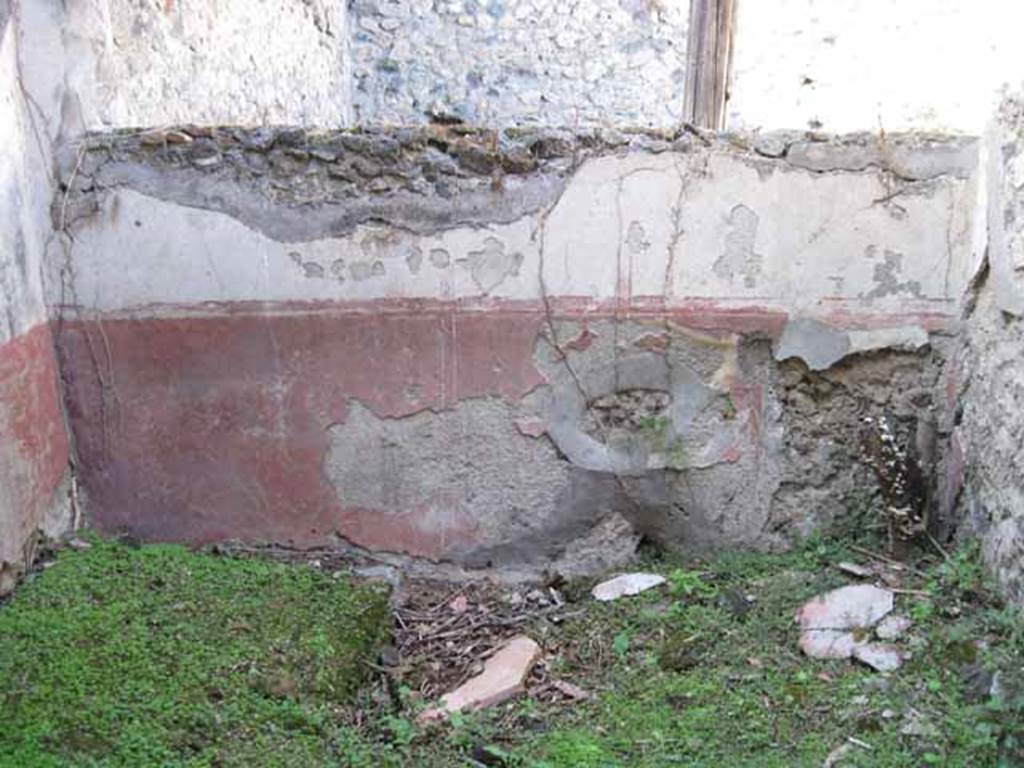 I.2.28 Pompeii. September 2010. North wall of room on south side of triclinium, with window onto garden area. Photo courtesy of Drew Baker.
According to Fiorelli, this room had access to a short underground passage for keeping provisions. See Pappalardo, U., 2001. La Descrizione di Pompei per Giuseppe Fiorelli (1875). Napoli: Massa Editore. (p.37)
According to Warscher, quoting Mau in Bull. Inst, 1874, p.250/51, she wrote 
Il peristilio, situate piu alto dell atrio a causa del terreno inuguale, ha corridoi di 3 e 3 colonne sui lati S ed E, mentre verso N ed O confina con le case adiacenti (I.2.17; I.2.22; I.2.24).  
Le colonne sono di mattoni e di stucco rozzo, color di carne fino allaltezza del muriciuolo che le congiunge, bianco di sopra.
La parte occidentale del portico meridionale, posteriormente soltanto, come ci fa testimonianza lo stucco delle colonne, coperto dal muro, ne fu separato e trasformata in una camera, che mediante una porta corrisponde colla camera a sinsitra del tablino, mentre verso N con una finestra larga, distante dal suolo m.1,52, si apre sul peristilio.
Sotto il pavimento di questa camera v un cavo, largo m. 0,98 + 0,67, profondo m. 1,32, rivestito di stucco e di sopra a met coperto, mentre lapertura che rimane evidentemente doveva chiudersi con un coperchio.
Sifatto cavo, il primo di questa sorta che si sia trovato a Pompei, serviva senza dubbio per conservare tutto ci, cher si voleva difendere dal caldo, facendo cos le veci duna piccola cantina.
Sul lato meridionale del peristilio vi  ancora un armadio stretto, aperto verso O, ed il cui fondo viene formato dal muro occidentale della camera a destra dellatrio, la quale sporge un poco nel peristilio.

