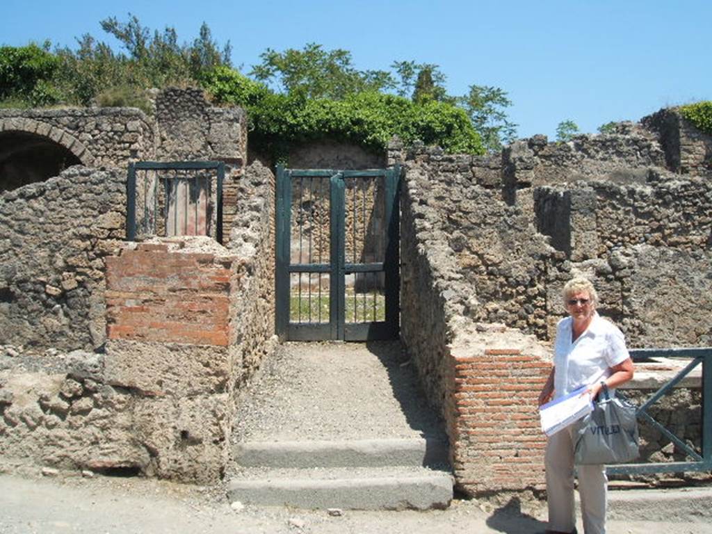 I.3.3 Pompeii. May 2005. Entrance on Via Stabiana. According to Warscher, quoting Bull. Inst, 1874, p. 183, she wrote 
Quanto alla pittura decorativa di questa casa, nella parte pi bassa di essa tutte le pitture mostrano lo stile degli ultimi tempi di Pompei, colleccezione della camera a destra della scala. 
Ed alla stessa epoca di quella camera, la terza cio fra quelle pompeiane, se non minganno, appartiene tutto quello che sta intorno al peristilio. Ho parlato appunto di questa casa nel Giorn. d Sc. II, p.456. Chiara  lidentita delle stile riguardo la prima camera dal suo lato occidentale. Il resto delle camere  decorato in uno stile che pu dirsi quello decandelabri, perch divide la parete in tre parti mediante candelabri molto sottili e svelti. E come accennai nel luogo citato, appunto le pitture di queste camere mediante certe piccole particularit non tanto facili a descriversi ci fanno riconoscere questo stile come affine e probabilmente contemporaneo a quello delle due camere menzionate. Ed allo stile di queste pare appartenesse anche la decorazione del peristilio stesso, bench poco ne sia conservato.
Que cambiamenti adunque che, come sopra accennai, sub la casa in discorso, si rileva dalla stessa decorazione che non ebbero luogo negli ultimi tempi di Pompei, ma probabilmente prima del terramoto della. 63 d.C.
See Warscher, T, 1935: Codex Topographicus Pompejanus, Regio I, 3: (dopo no. 11a), Rome, DAIR.  
