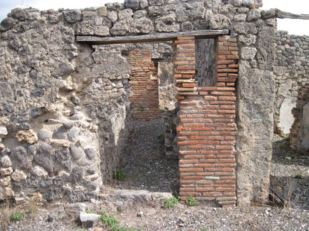 I.3.8b Pompeii. September 2010. 
Looking east towards south-central doorway from east portico of peristyle, towards kitchen at rear. Photo courtesy of Drew Baker.
According to Boyce, somewhere along the east wall of the peristyle was a niche.
In the niche, a terracotta statuette of Minerva was found.
She was wearing a helmet and holding a shield on her left arm and holding a patera in her right hand.
See Boyce G. K., 1937. Corpus of the Lararia of Pompeii. Rome: MAAR 14. (p.24, no.22)
Giornali degli Scavi, N.S. I, 1869, p. 301.
Boyce gave a note 1 on page 24, to this entry. It read –
In a room opening off the east side of the peristyle a bronze statuette of Fortuna was found.
She was holding a cornucopia against her left shoulder.
Giornali degli Scavi, N.S., i, 1869, 305. 
According to Giacobello – the niche is no longer conserved.
See Giacobello, F., 2008. Larari Pompeiani: Iconografia e culto dei Lari in ambito domestico. Milano: LED Edizioni, (p.252, no.V3)


