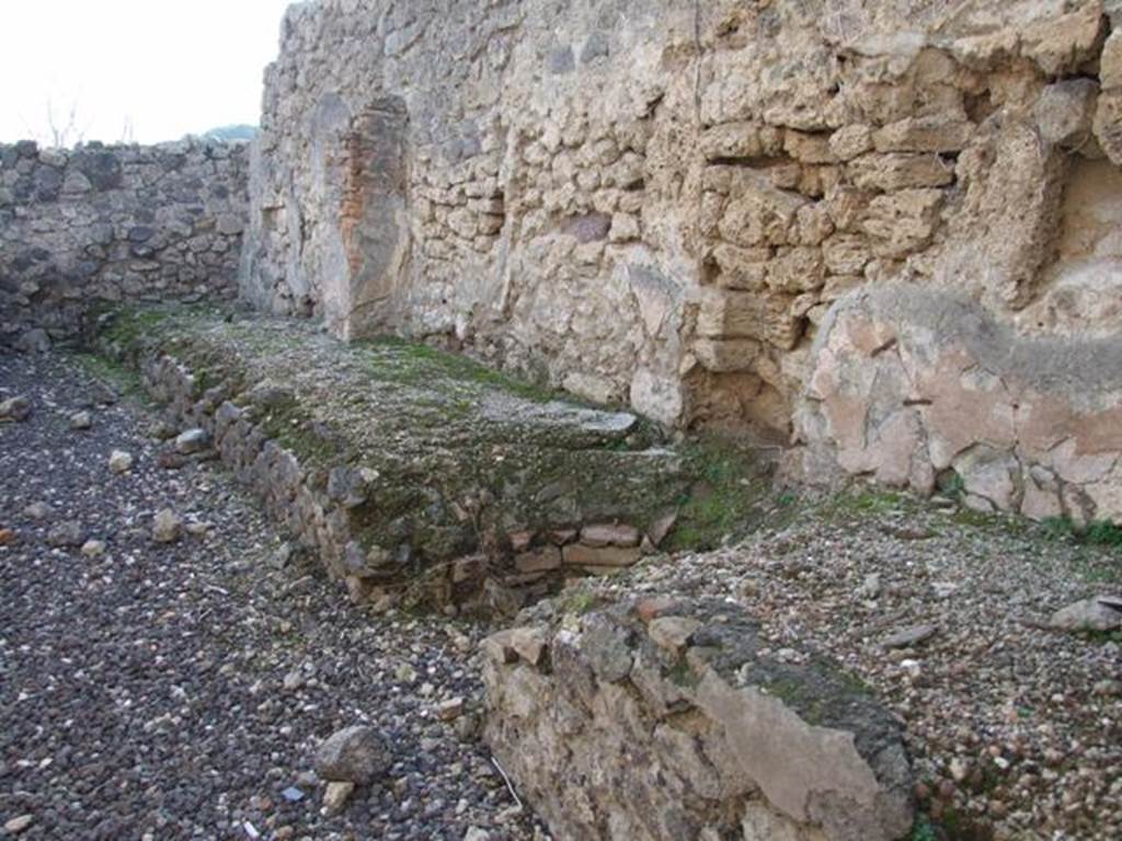 I.3.16 Pompeii. December 2007. West wall with remains of podium.  This used to have two tubs at the south end.  The boiler, the round gap in the centre of the picture, was used to heat a vessel. 
