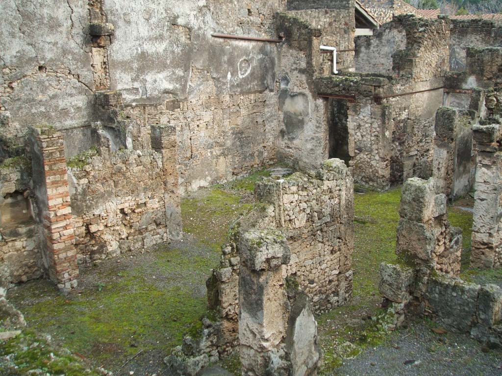 I.6.13 Pompeii. December 2004. Tablinum, atrium and east side looking south-east photo taken from rear of I.6.11. 
Behind the east wall of the tablinum, on left, would be the cubiculum (5) in NE corner of atrium.
Room 7 with doorway to corridor e is on the lower right, the corridor e is on the west side of the tablinum.
The remains of a lararium niche are on left of picture, in garden area behind tablinum.
According to Boyce 
In the east wall of the garden is an arched niche (height 0.40, width 0.60, depth 0.27, height above the floor 1.30).
This was referred to in the report as un modesto larario.
See Boyce G. K., 1937. Corpus of the Lararia of Pompeii. Rome: MAAR 14. (p. 25, no.38) 
He quotes reference Not. Scavi, 1929, p.434.
