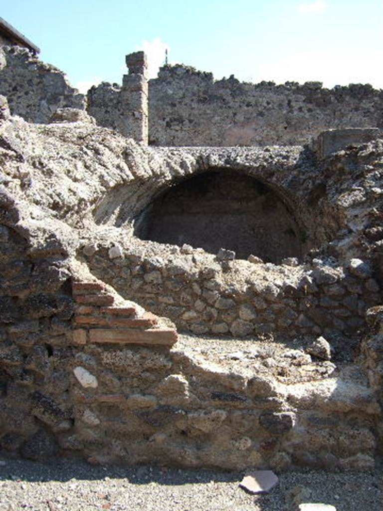 I.8.2 Pompeii. September 2005. Remains of peristyle on top of cistern and cellars, near entrance I.8.19 Looking east from small vicolo towards cistern at lower level, with peristyle of I.8.2 above. According to Jashemski, part of the floor on the north, east and west portico of the peristyle, was destroyed by the 1943 bombing.   A gutter at the edge of the garden collected rain water which was stored in the large cistern under the peristyle. The water appeared to have been used in the adjacent dye-shop (I.8.19) at the rear. See Jashemski, W. F., 1993. The Gardens of Pompeii, Volume II: Appendices. New York: Caratzas. (p.42)
