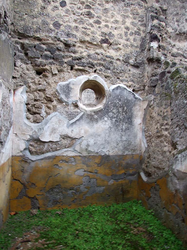 I.8.14 Pompeii. December 2007. Room 2, east wall of cubiculum with circular window. 
The high zoccolo was yellow, and the middle zone of the wall was white showing vignettes with borders in panels separated by compartments painted with golden candelabra.
