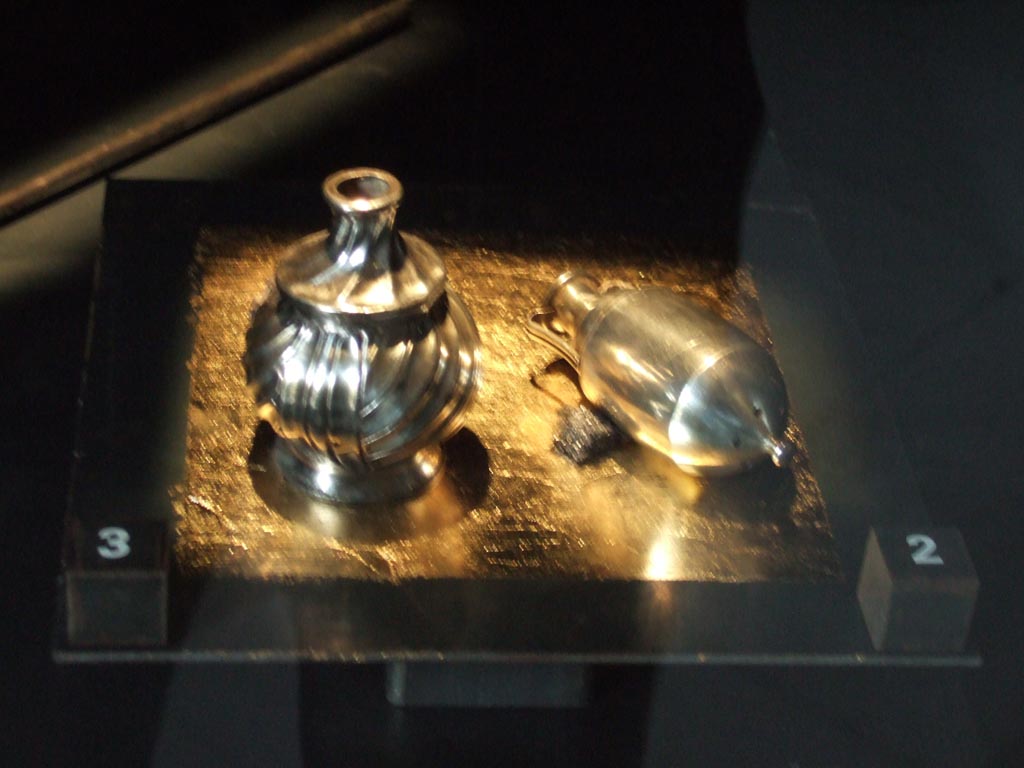 I.10.4 Pompeii. Silver pepper pots. One has the shape of a small amphora.
The other has the shape of an aryballos (a small spherical flask).
Part of the 115 pieces of Silver found in a chest in the underground storerooms. 
Now in Naples Archaeological Museum. Inventory numbers 145556 (right) and 145557 (left).
See Guzzo, P. (A cura di), 2006. Argenti a Pompei. Milano, Electa. p.222.
