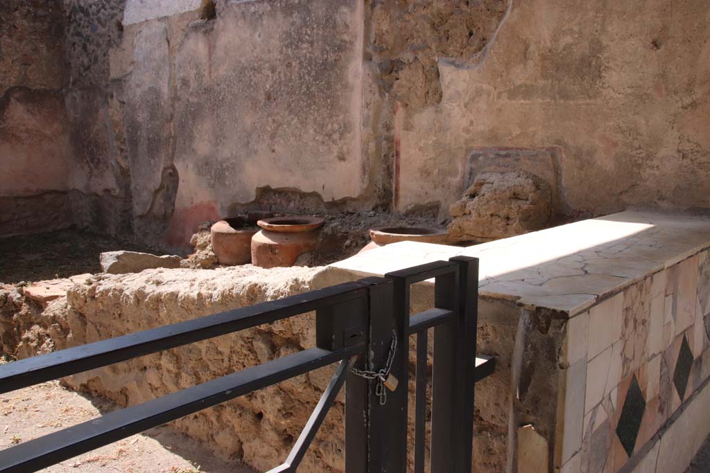 1.11.1 Pompeii. September 2019. 
Looking towards west side with remains of four urns and shelves for displaying drinking vessels. Photo courtesy of Klaus Heese.
