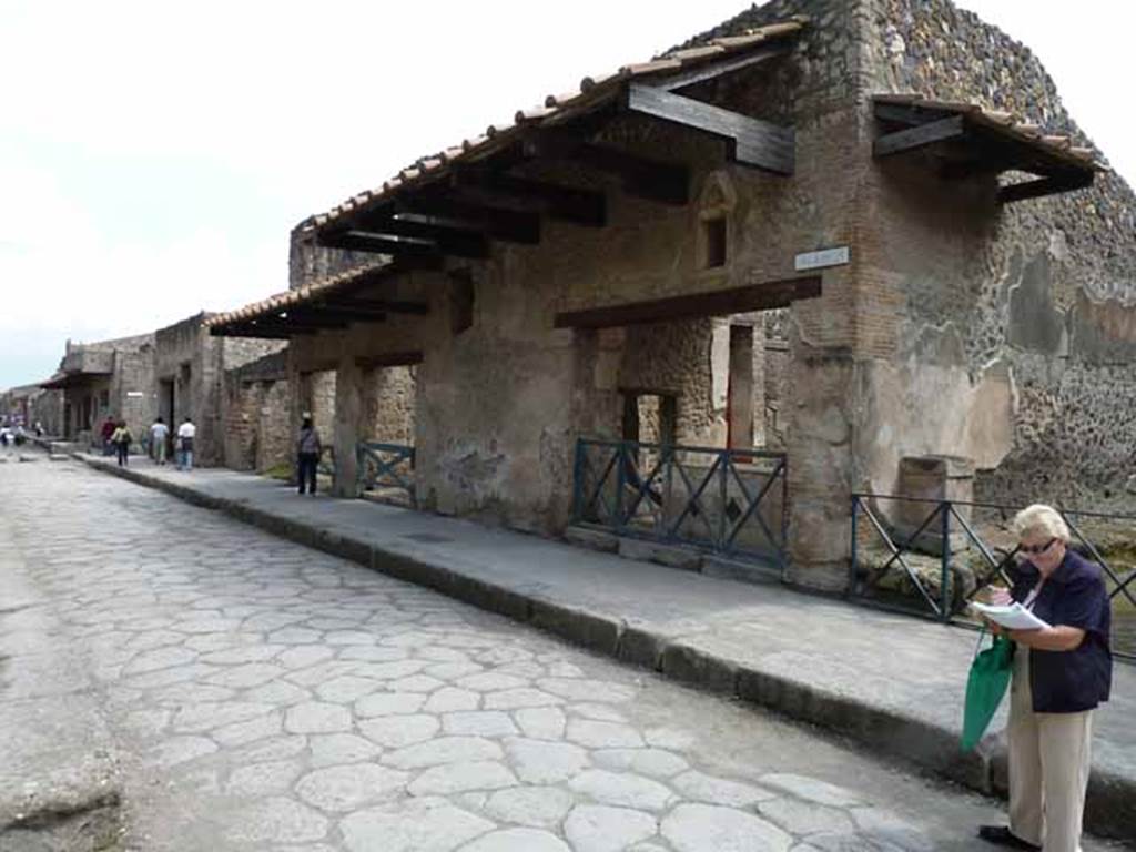 Via dell’Abbondanza, south side. May 2010. Looking east from near unnamed vicolo towards I.11.  I.11.1 is the doorway on the right of the photo.  Above the doorways of I.11.2, left of centre, and I.11.3, left of I.11.2, windows can be seen in the upper floor.  
According to Della Corte,  “Reg. II, ins.1, on high between doorways 1 and 2, a window was found (0.80m wide x 1.20m high), protected by a grating which remains in its place in reasonable state of preservation; beyond the described window and continuing towards the east, and it seems placed above doorways 2 and 3, a large roof was found a little knocked down from its original position, about 6m. long (but the eastern extremity has not yet been discovered), and protruding by just over 2m.  At the rear of the wall of the façade of doorway 1, definitely in their place were the remains of the basins/tubs mentioned last month, putting all the fragments of one of them back into its place with its bottom. "  See Notizie degli Scavi, 1913, p.220.
(Reg. II, ins. 1. Tra i vani 1 e 2 in alto, si e scoperta una finestra (larga 0.80m. alta 1.20m) protetta da inferriata che resta tuttora al suo posto in discreto stato di conservazione; oltre la descritta finestra, procedende sempre verso oriente, e quindi imposta sul vani 2 e 3 come pare, si era rinvenuta, di poco abbattuta dalla sua originaria posizione, una grande tettoia, lunga per ora (non se ne era ancora scoperta l’extremita orientale) 6m, e sporgente per poco piu di m.2.  A tergo del muro di facciata del vano 1 si sono definitivamente assicurati al posto loro gli avanzi delle vasche accennate il mese scorso, rimettendo a posto interamente i frammenti di una di esse col relativo fondo.”)
