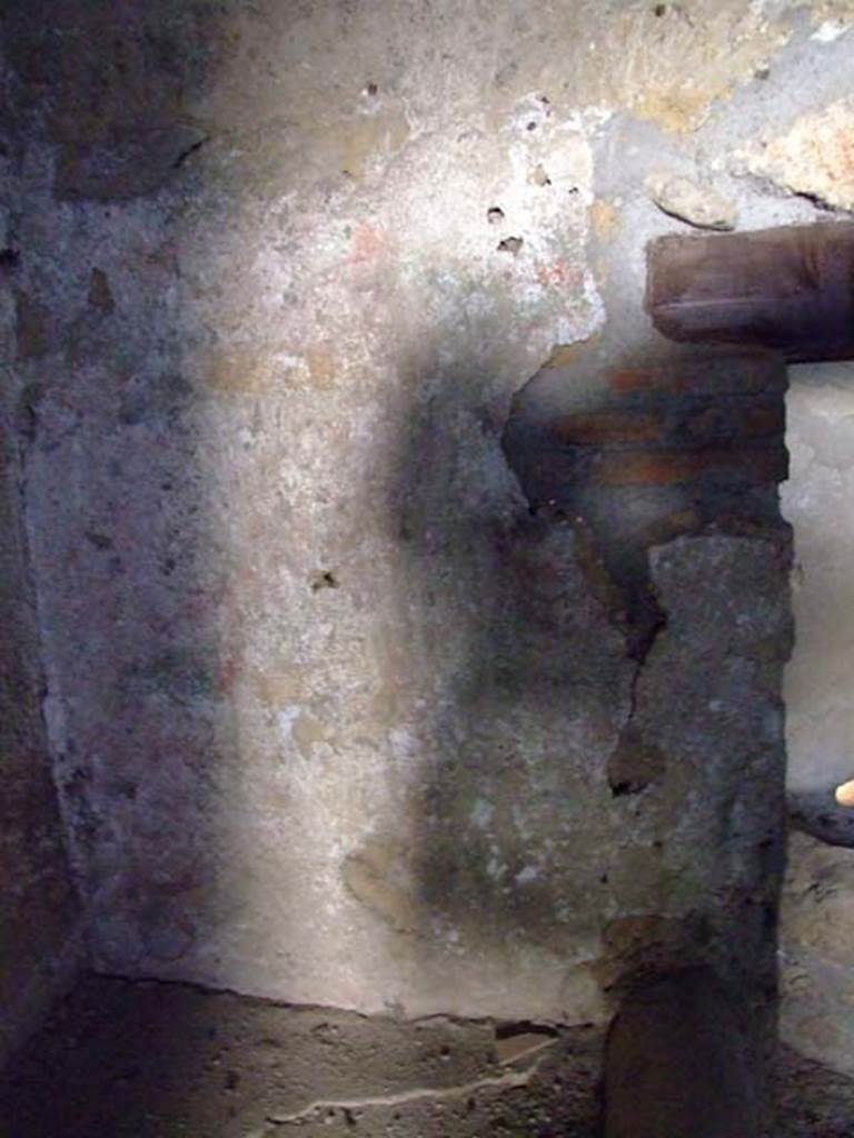 I.12.11 Pompeii. March 2009. Lararium painting on west wall of kitchen, above hearth.  
According to Giacobello, the lararium painting in the south-west corner of the kitchen was on the walls that against which the bench was placed.
It was not very preserved, but showed garlands in red/yellow/green, with underneath them a trace of sky blue.
See Giacobello, F., 2008. Larari Pompeiani: Iconografia e culto dei Lari in ambito domestico.  Milano: LED Edizioni. (p. 154).
