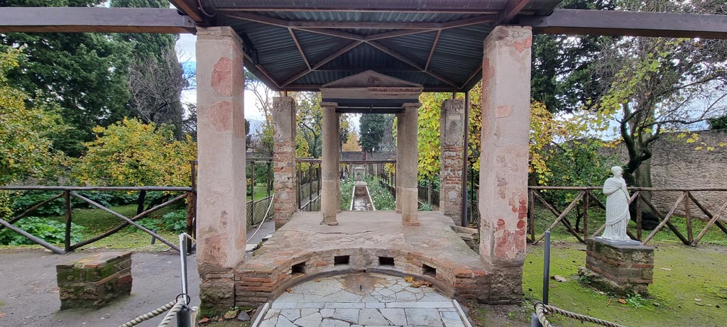 II.2.2 Pompeii. December 2023.
Room “i”, looking south to temple at junction of upper and lower euripus, see room “l” (L) for further photos of the lower garden area.
Photo courtesy of Miriam Colomer.
