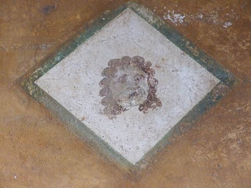 II.3.3 Pompeii. December 2006. Room 11, west portico. Diamond shaped wall painting of a face.