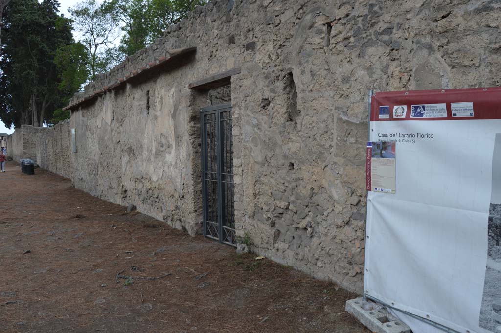 II.3.8 Pompeii. October 2017. Looking towards entrance doorway and west along front façade towards II.3.9.
(Note: the notice-board with mention of Casa del Larario Fiorito, II.9.5, is nothing to do with the house here, II.3.8).
Foto Taylor Lauritsen, ERC Grant 681269 DÉCOR.


