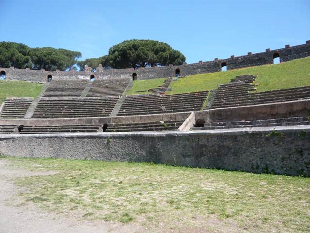 II.6 Pompeii. May 2012. North-east rim of inner wall of the arena of the Amphitheatre where inscriptions are carved.  
Photo courtesy of Buzz Ferebee.
According to Cooley, in a series of inscriptions [CIL X, 853, 854, 855, 856, 857a, 857d] on the capping of the wall dividing the arena from the spectators’ seating appear the names of benefactors, who paid for the construction of the stone seating during the Augustan period. 
This replaced the earliest seating, which was probably wooden.
Each inscription relates to a particular section, or wedge, of seating (cuneus). 
See Cooley, A. and M.G.L., 2004. Pompeii: A Sourcebook. London: Routledge, p. 46.
