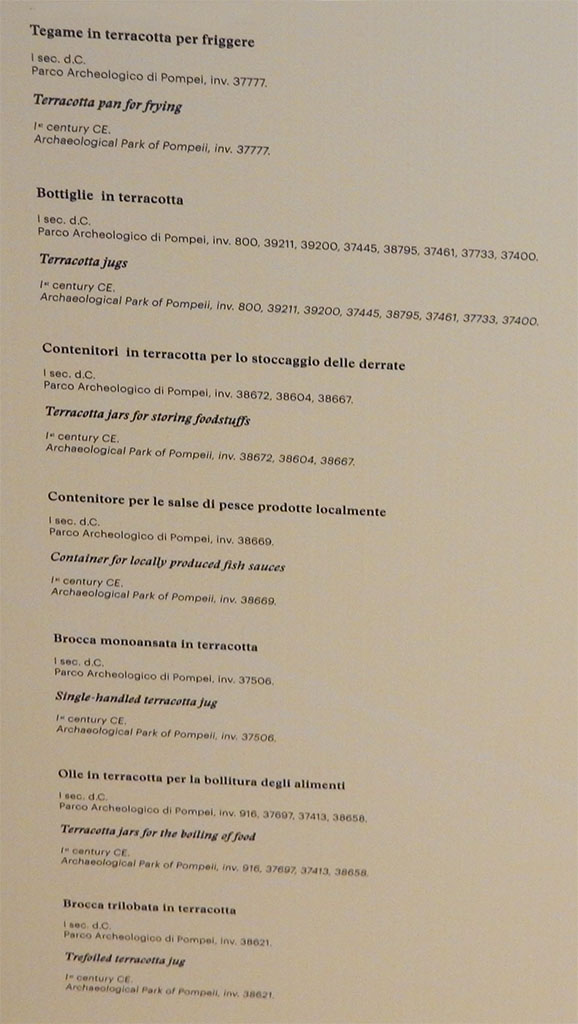 II.9.5 Pompeii, May 2018. Display notice on cabinet. Photo courtesy of Buzz Ferebee.
Terracotta pan for frying (Tegame in terracotta per friggere), inv. no. 37777
Terracotta jugs (Bottiglie in terracotta), inv. nos. 800, 39211, 39200, 37445, 38795, 37461, 37733, 37400
Terracotta jars for storing foodstuffs (Contenitori in terracotta per lo stoccaggio delle derrate), inv. nos. 38672, 38604, 38667
Container for locally produced fish sauces (Contenitore per le salse di pesce prodotte localmente), inv. no. 38669
Single-handled terracotta jug (Brocca monoansata in terracotta), inv. no. 37506
Terracotta jars for the boiling of food (Olle in terracotta per la bollitura degli alimenti), inv. nos. 916, 37697, 37413, 38658
Trefoiled terracotta jug (Brocca trilobata in terracotta), inv. no. 38621
All inventory numbers are of Archaeological Park of Pompeii.
