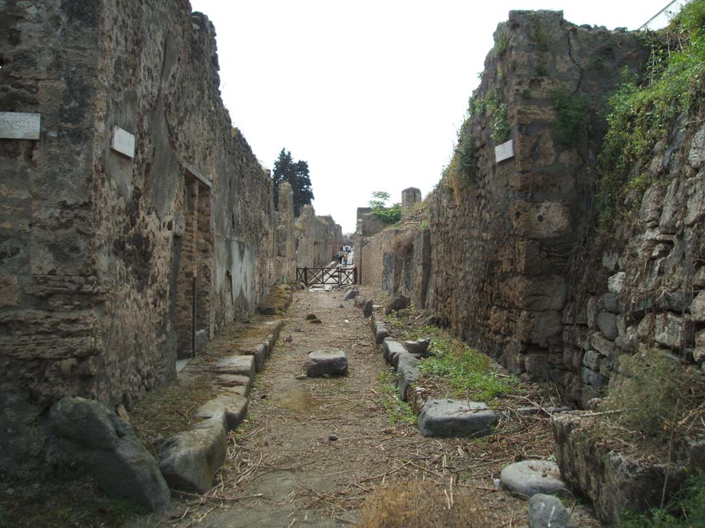 V.1.11 (corner), on left. May 2005. Looking west along Vicolo delle Nozze d’Argento. V.6, and unexcavated roadway, on right.