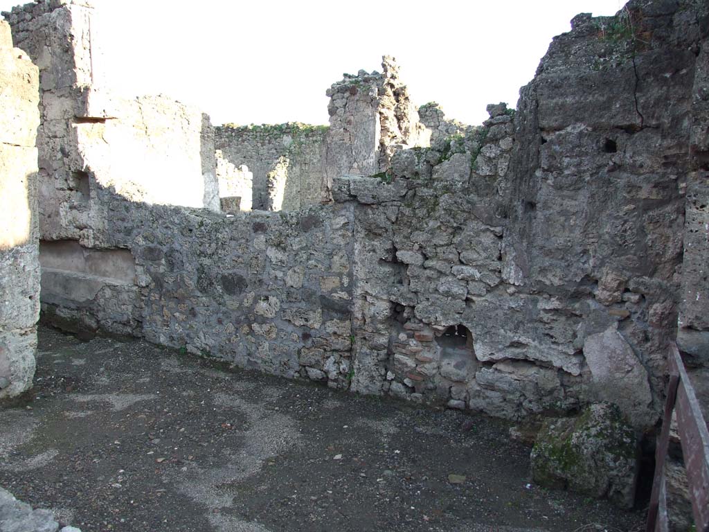 V.I.13 Pompeii. December 2006. South wall.
According to Boyce, in the south wall of the corridor that led towards the rear was an arched niche.
In the rear wall of the niche there was a small vaulted recess, for a statuette.
See Boyce G. K., 1937. Corpus of the Lararia of Pompeii. Rome: MAAR 14. (p.32, no.73) 
