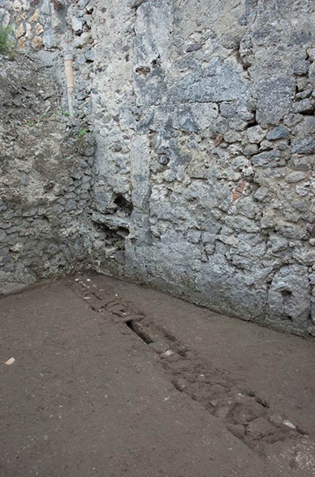 V.1.15 Pompeii. c.2012. Room “f”. 
“Looking across flooring towards south-east corner, showing how conduit probably meets up with the vertical terracotta pipe embedded in the south wall.” Photo by Hans Thorwid.
Photo and words courtesy of the Swedish Pompeii Project.
