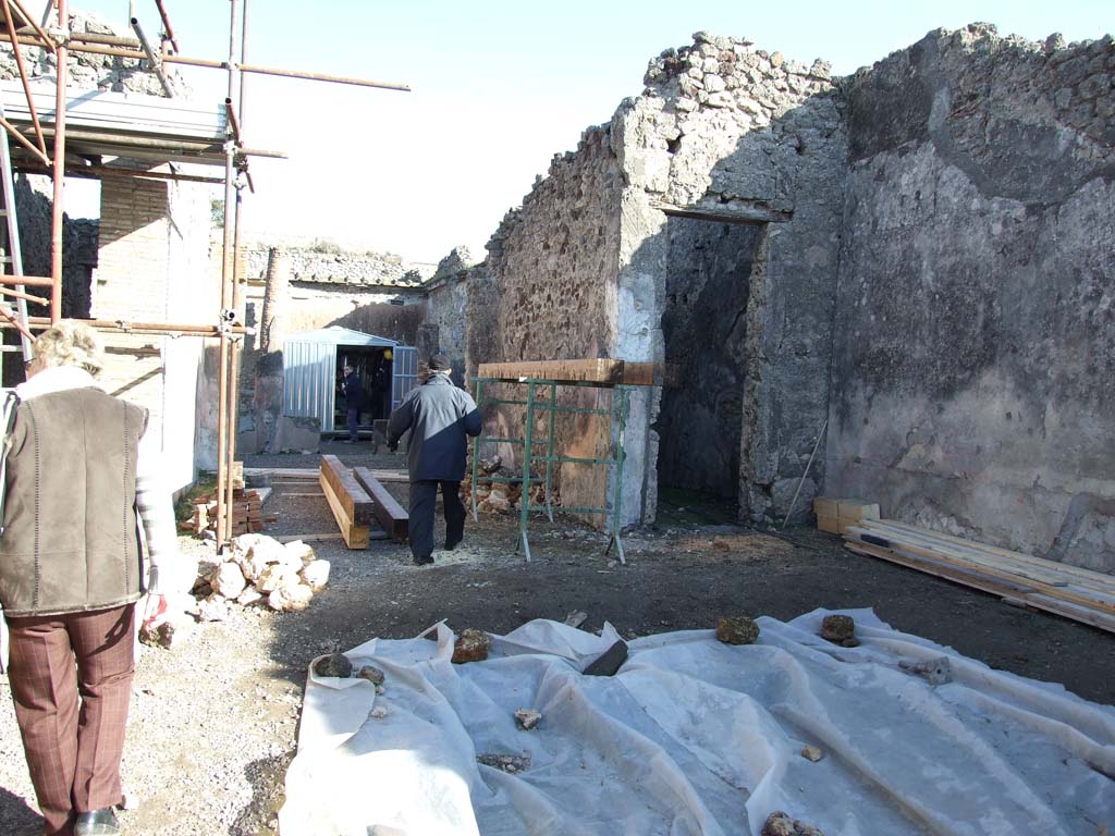 V.1.18 Pompeii. December 2007. Looking east across atrium to tablinum “g” and room “f”.
According to Mau, there were large red panels, divided by narrow black strips each containing a yellow candelabra.
In the centre each red panel was a medallion with the bust of a divinity.
There were originally seven medallions with busts of gods and goddesses, but one had vanished.
The execution was not diligent, but with enough skill to look good for those who do not look too closely.
At the top were black outlined rectangles on a white background with second rectangle with red lines inside each.
See Bullettino dell’Instituto di Corrispondenza Archeologica (DAIR), 1877, p. 20.
