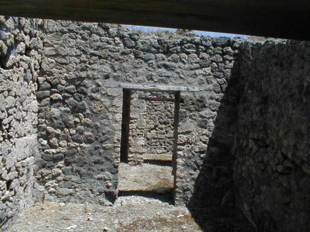 V.1.20 Pompeii. May 2005. Doorway from rear room, towards kitchen, small garden and cubiculum. According to Jashemski -  “The tiny garden (a) excavated in 1875, in the rear north-east corner of this small shop-house wedged in between 2 large houses was little more than a light well enclosed by a low wall with a gutter at the base; along the inside of the gutter, according to Viola, there was a narrow planting bed.  The kitchen (b) opened onto the garden."
See Mau, Bdl (1877), p.18
See Viola, Gli Scavi di Pompei dal 1873 al 1878, p.28.
See Jashemski, W. F., 1993. The Gardens of Pompeii, Volume II: Appendices. New York: Caratzas. (p.108)
