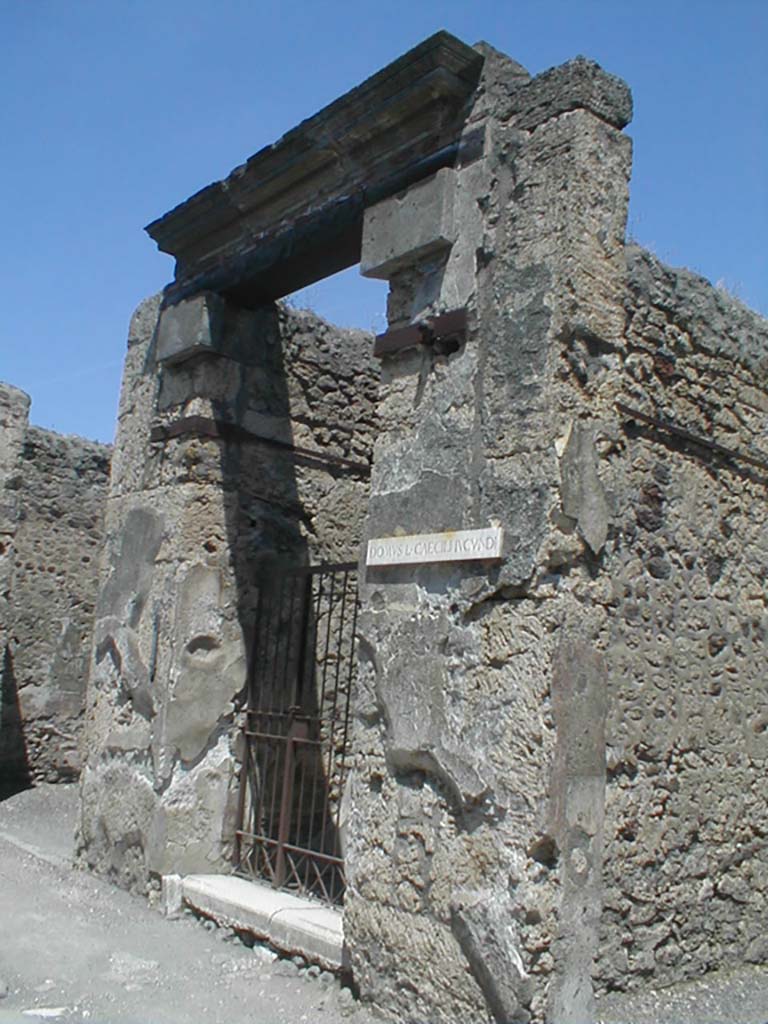 V.1.26 Pompeii. May 2005. Entrance with name plaque DOMUS L CAECILI IUCUNDI.
Many electoral programmes were written on the façade:

[M.]  Holconium  Priscum  II  vir(um)  i(ure)  d(icundo)
d(ignum)  r(e)  p(ublica)  o(ro)  v(os)  f(aciatis)
IVCVNDVS  ROGAT   [CIL IV 3428]
According to Della Corte, this was written to the right of the main entrance doorway at 26.

He also quotes:
[L.]  Ceium  Secundum –  II  vir(um)
Q(VINTVS)  S(EXTVS)  CAECILI   IVCVNDI   ROGAMVS  [CIL IV 3433].
Della Corte says the second programme was found on the pilaster to the right of the next shop at number 27.
This shop was part of the same house.
See Della Corte, M., 1965. Case ed Abitanti di Pompei. Napoli: Fausto Fiorentino. (p.18)

According to Cooley, the following was found on the façade of the house:
We, Quintus and Sextus Caecilius Iucundus, ask for Ceius Secundus as duumvir. [CIL IV 3433 = ILS 6404a]
See Cooley, A. and M.G.L., 2004. Pompeii: A Sourcebook. London: Routledge. (F17 on p. 116)
