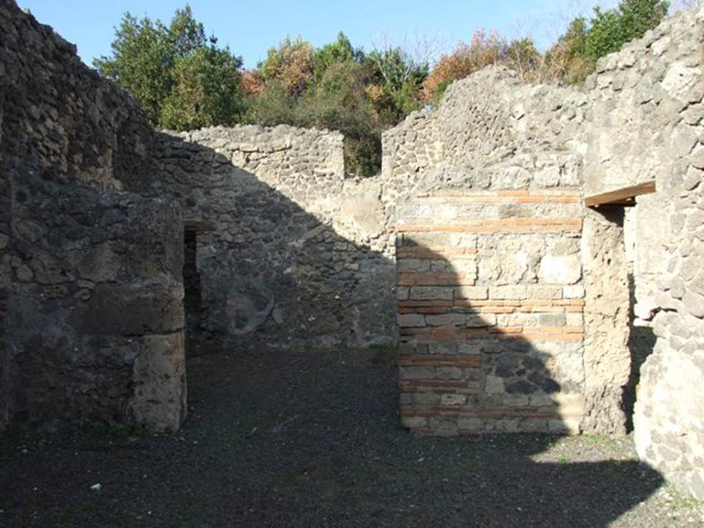 V.2.17 Pompeii. December 2007. Looking north across shop to doorway to middle room.
According to NdS, when excavated the shop was found with a sales counter, covered with plaster imitating coloured marble and decorated with a painting (0.79 x 0.51).
The painting showed Teti (Thetis? or Tethys?) dressed in a pink robe sitting on a bearded Triton, and armed with helmet, shield and breast-plate. While she held the shield on the back of the monster with the left hand, she grasped the lance in her right-hand, that the Triton carried on his shoulders. The Triton was swimming towards the left and turning his gaze to the goddess. See Notizie degli Scavi, October 1877, (p.60)

