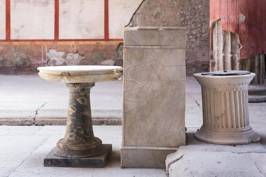 V.2.i Pompeii. August 2023. Room 1, atrium, south end of impluvium. 
Looking east towards stone basin on stand, rectangular marble base and travertine puteal. Photo courtesy of Johannes Eber.

