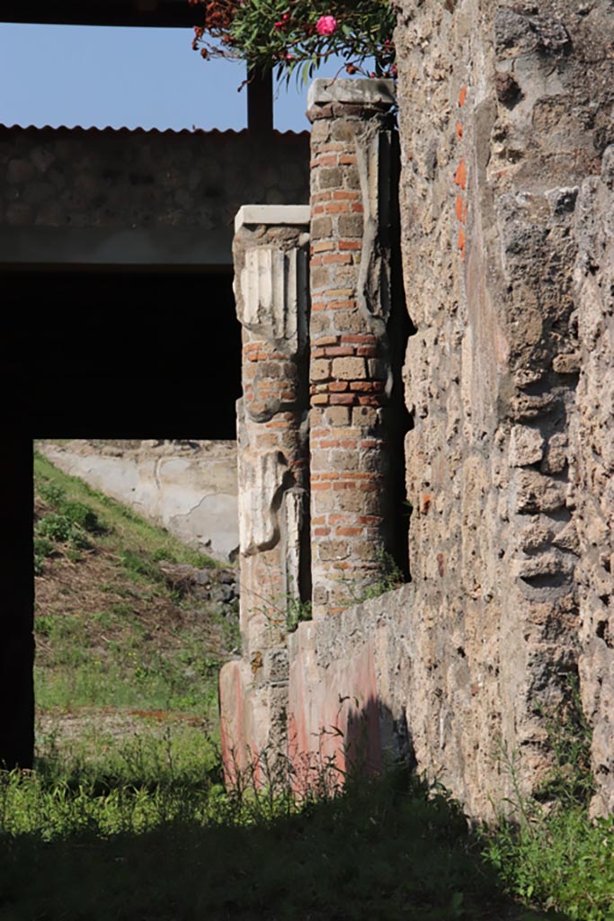 V.3.4 Pompeii. October 2023. 
Looking north from entrance doorway towards two white stuccoed columns on west side of garden, which supported the west and partial north portico.
Photo courtesy of Klaus Heese.
