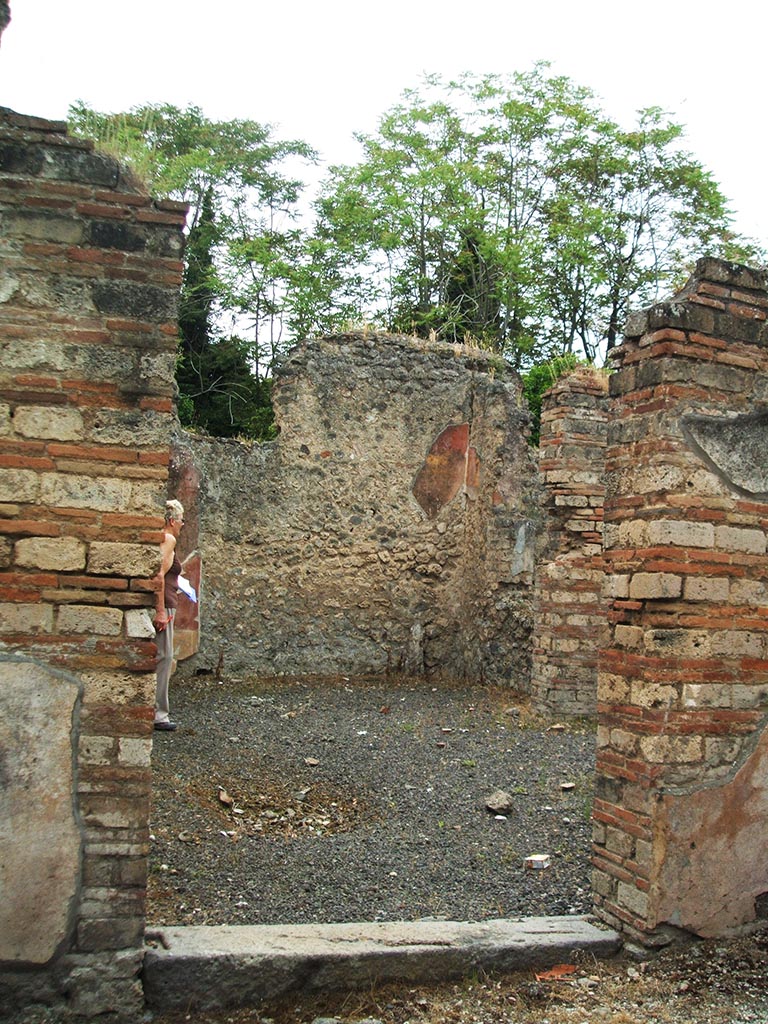 V.3.9 Pompeii. May 2005. Entrance doorway, looking west.
According to NdS, the entrance threshold stone was made of lava, and led into a poor little house of modest appearance.
The door jambs were brick and opened immediately into the atrium.
In the corner, to the left of the doorway as one entered, was a cistern with a terracotta puteal in which it seemed the rainwater would have emptied by a clay pipe, now disappeared. The puteal was covered with stucco, coloured red.
The impluvium had been eliminated in a make-over of the house, however traces of it can be seen in the flooring of the atrium.
The floor of the atrium was decorated with triangular pieces of different marbles.
See Notizie degli Scavi di Antichità, 1902, dated November 1901, p.201-203.
