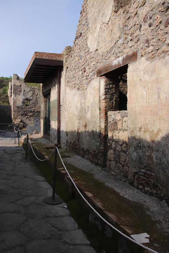 Vicolo dei Balconi, Pompeii. October 2022. 
Looking north to Thermopolium of Nereid (doorway B1) with reconstructed balcony at junction with Vicolo delle Nozze d’Argento. 
In the centre is another house entrance, we number as B2, with a blocked entrance. Photo courtesy of Klaus Heese.

