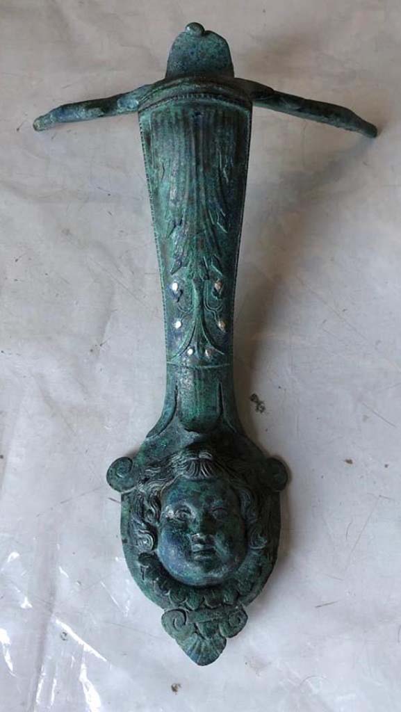 V.3 Pompeii. Casa del Giardino. 2018. Bronze handle with head and inset silver.

Maniglia in bronzo con testa e argento incassato.  

Photograph © Parco Archeologico di Pompei.
