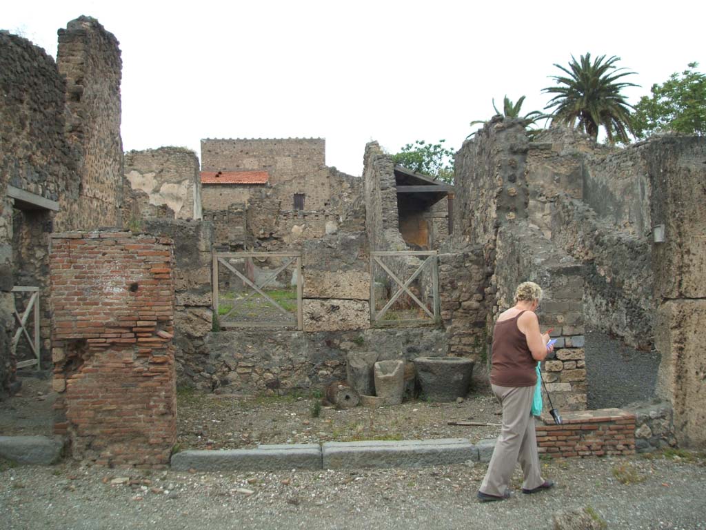 V.4.2 Pompeii. May 2005. Entrance on Via di Nola, looking north.
According to Boyce, a terracotta statuette of Minerva was found in this shop.
She was wearing a helmet, shield and aegis and holding a patera in her right hand.
The figure showed traces of its original colouring.
See Notizie degli Scavi di Antichità, 1889, 133, 
See Bullettino dell’Instituto di Corrispondenza Archeologica (DAIR), xvi, 1901, 312.
See Boyce G. K., 1937. Corpus of the Lararia of Pompeii. Rome: MAAR 14. (p.108, no.3). 
