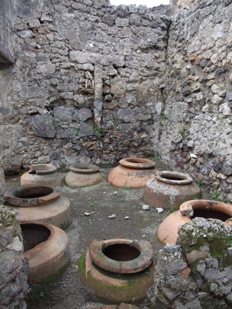 V.4.7 Pompeii. December 2007. Vinarium with eight dolia in north-west corner.
Looking west across vinarium, with doorway in south wall, on left, leading towards V.4.6.
According to Boyce, a small marble altar was found in this room. 
It was decorated on the front face with a taenia (band), a patera (shallow dish) and an urceus (one handled jug). 
The upper surface was divided into two sections by a ridge down the centre.
See Boyce G. K., 1937. Corpus of the Lararia of Pompeii. Rome: MAAR 14. (121; p. 40, note 2).
