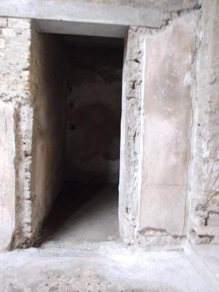 VI.8.5 Pompeii. March 2009. Doorway to room 8, storeroom on west side of atrium.
This room, storeroom or cubiculum, would have had a red zoccolo, nearly all of which has faded; a yellow middle zone to the walls, panels bordered by “carpet” design separated by a white compartment with traces of candelabra; in the upper zone were architectural elements.
