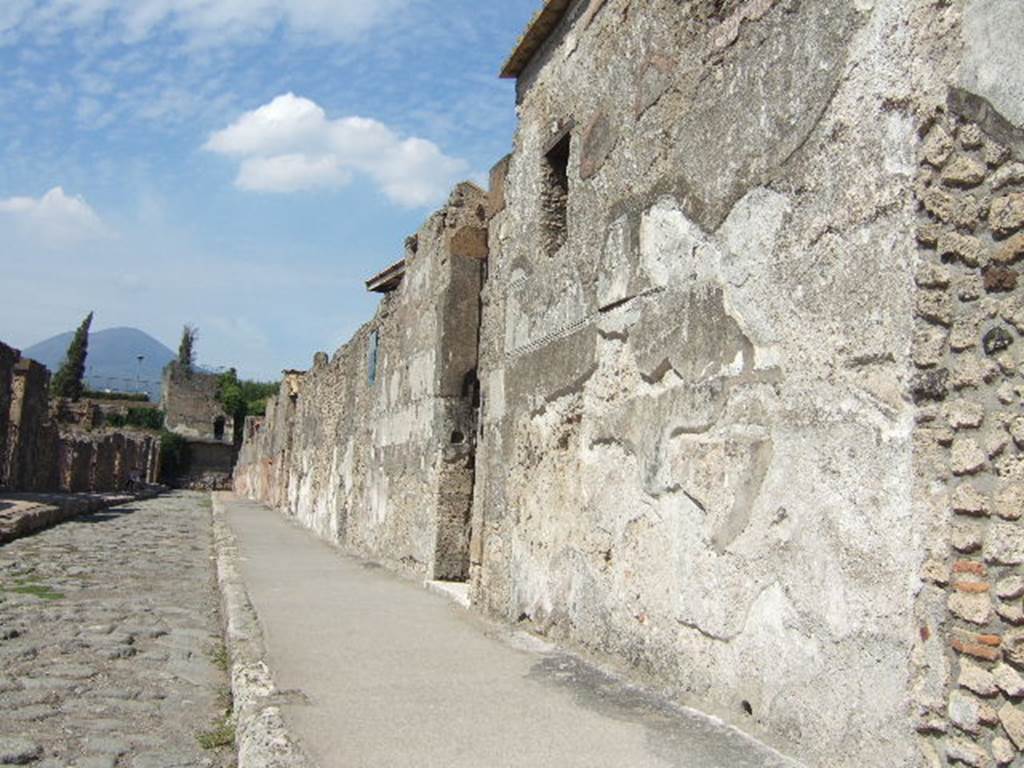 VI.9.6 Pompeii. September 2005.  Looking north past entrance on Via di Mercurio from outside VI.9.7. Fiorelli thought that one patron owned all of the remaining big house of the insula (VI.9.6/7), and he had it decorated externally with a red painted podium but this was covered and degraded by much graffiti and writings, one of the most notable recording the fight between the Nucerians and Pompeians
Campani  Victoria  una
cum  Nucerinus  peristis
See Pappalardo, U., 2001. La Descrizione di Pompei per Giuseppe Fiorelli (1875). Napoli: Massa Editore. (p.65)
According to Cooley, this translates as “Campanians, in our victory you perished with the Nucerians”. [CIL IV 1293, ILS 6443a]
See Cooley, A. and M.G.L., 2004. Pompeii : A Sourcebook. London : Routledge. (p.62)

According to Pagano and Prisciandaro, found in September or October 1828, written with an iron point in small letters, was the inscription –
Campani  Victoria  una
cum  Nucerinus  peristis     [CIL IV 1293]
See Pagano, M. and Prisciandaro, R., 2006. Studio sulle provenienze degli oggetti rinvenuti negli scavi borbonici del regno di Napoli.  Naples : Nicola Longobardi. (p.139) and PAH II, 215-6.

According to Breton, on the facade one could read many inscriptions but by then (1870) many were faded and unreadable, but many had also been published. 
See Breton, Ernest, 1870. Pompeia, Guide de visite a Pompei, 3rd ed. Paris, Guerin.
See Epigraphik-Datenbank Clauss/Slaby (See www.manfredclauss.de)
