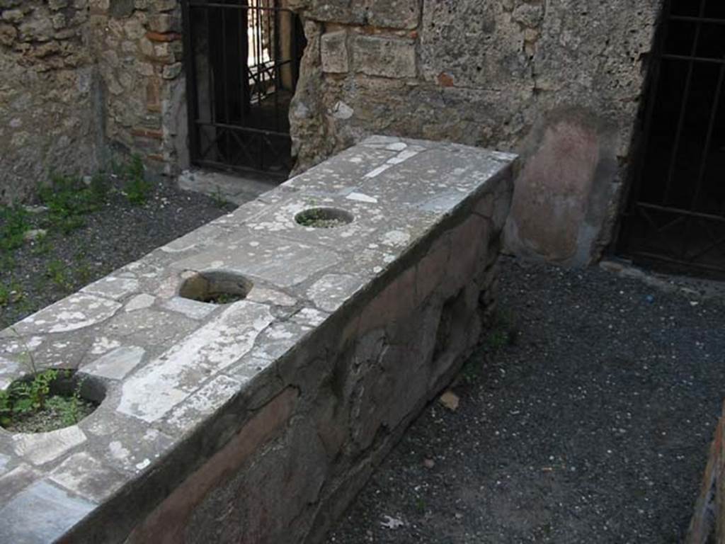 VI.10.1 Pompeii. May 2003. Marble counter with three urns. Looking towards the east wall, the door on the left leads into the room on the north side (also see VI.10.19).
The doorway on the right leads into the room on the south side of the bar, and probably originally linked to VI.10.2 Photo courtesy of Nicolas Monteix.
