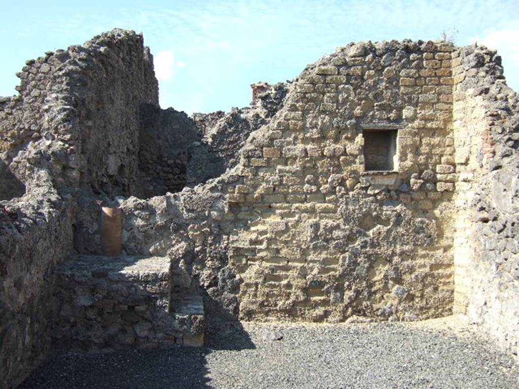 VI.14.4 Pompeii. September 2005. North wall with base of steps to upper floor in north-west corner. Behind the steps can be seen a down-pipe from the upper floor. 
