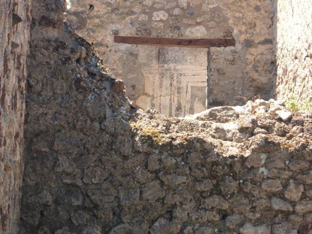 VI.14.26 Pompeii. May 2005. Looking west over rear wall towards doorway and painted wall decoration from VI.14.25, showing repaired wall/doorway.
