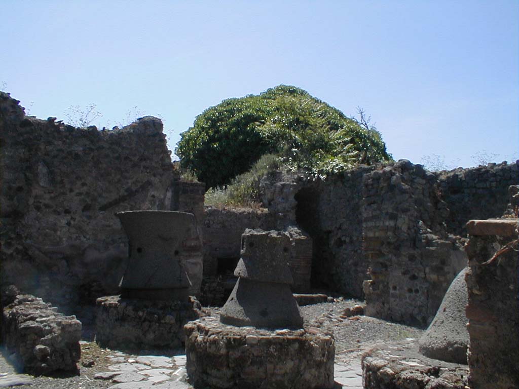 VI.14.32 Pompeii. May 2005. Looking south-west from room to east of entrance doorway across mills towards oven.  
This room is shown on the Eschebach plan as the location of entrance 32. 
At Pompeii, the entrance numbered 32 is actually a short distance further west, looking into the mill room.
