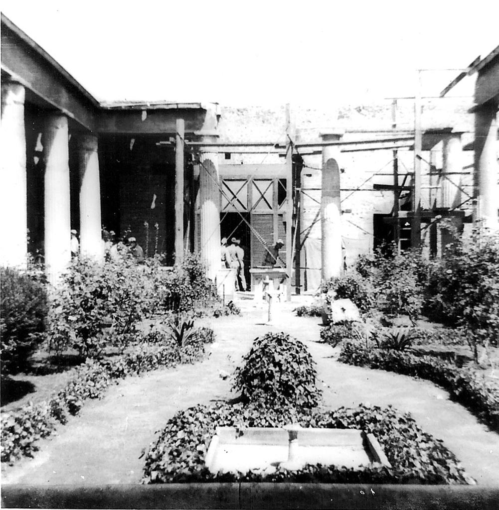 VI.15.1 Pompeii. 1944. Peristyle garden, looking north. Photo courtesy of Rick Bauer.
According to Garcia y Garcia, not even the most famous house in Pompeii was saved from the 1943 bombardment.
The troops of tourists that have visited there each day, are mostly ignorant of the reality of the events.
On the night of 16th September 1943, a bomb fell and destroyed the north-east corner of the peristyle causing the subsidence of the floor of the peristyle.
This also caused the destruction of a part of the north perimeter wall, the ruin of three columns in the peristyle, and the partial loss of the IV style painted wall from the north portico, and the west wall of the peristyle.
Damage was also suffered in the south-west part of the triclinium and the north wall of the oecus of Pasiphae, to the north-east of the peristyle.
The south corner of the women’s gynaeceum to the north of the peristyle was also partially ruined.
In the south-east corner of this area was the triclinium decorated with the painting of Hercules and Auge on the south wall. 
This was damaged in its lower parts, without the possibility of restoration. 
Partially damaged was the roof of the walkways around the peristyle, and that of the oecus of Pasiphae, and in the cubiculum to the north of the atrium.
The other paintings in the house were saved by a miracle.
See Garcia y Garcia, L., 2006. Danni di guerra a Pompei. Rome: L’Erma di Bretschneider. (p.93-96, including photos).
